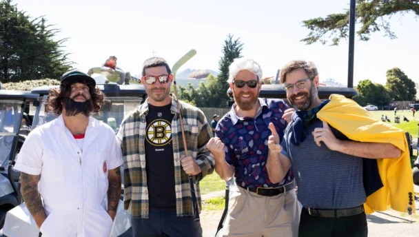 Group of four adults in costume ready to play in a golf tournament.